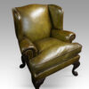 Antique Irish green leather wingchairs at angle