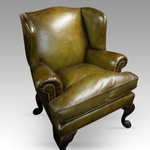 Antique Irish green leather wingchairs at angle