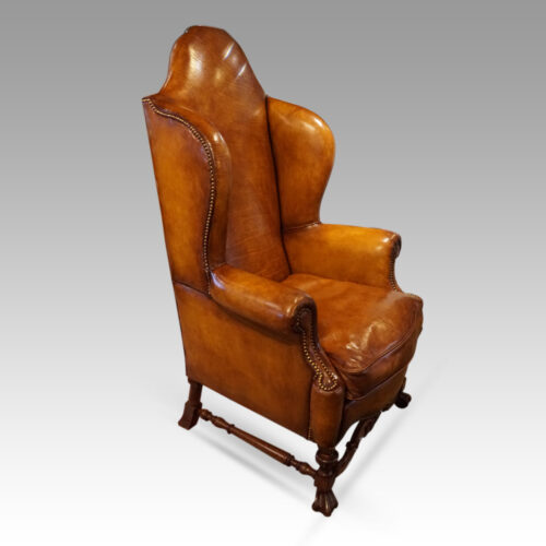 Pair of walnut leather wing chairs at angle