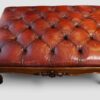 Victorian walnut ottoman with buttoned red leather upholstery and carved cabriole legs.