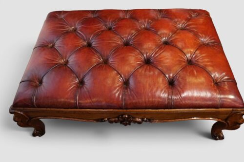 Victorian walnut ottoman with buttoned red leather upholstery and carved cabriole legs.