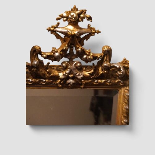 Decorative antique trapezoidal mirror with richly ornamented gilt and silver-gilt frame