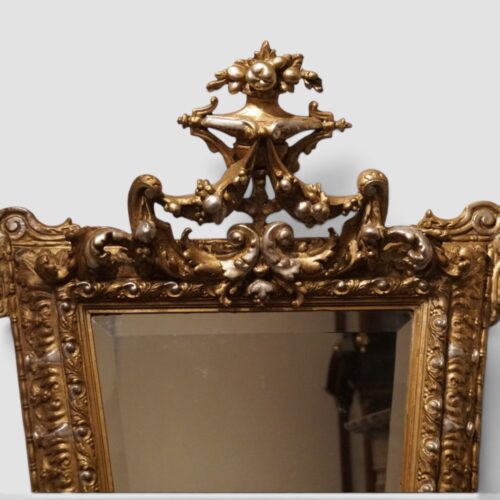 Antique gilt mirror showing elaborate upper crest and silver-gilt detailing