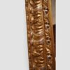 Ornate antique trapezoidal wall mirror with decorative gilt frame and crest