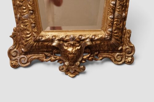 Large antique gilt trapezoidal mirror with elaborate carved ornamental frame