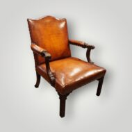 Front view of a large Georgian Gainsborough mahogany armchair upholstered in hand-dyed English hide leather with carved arms and brass stud detailing.