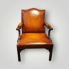 Front view of a large Georgian Gainsborough mahogany armchair upholstered in hand-dyed English hide leather with carved arms and brass stud detailing.