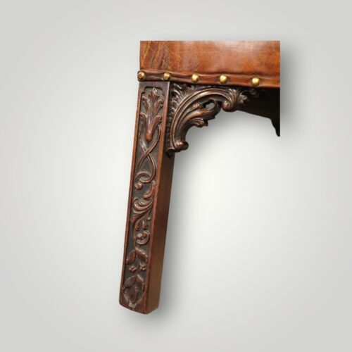 Close-up of the carved front leg showing Chippendale blind fret carving and decorative carved bracket on a Georgian mahogany Gainsborough chair.