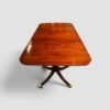 Antique extending mahogany dining table shown with its twin pillar base.