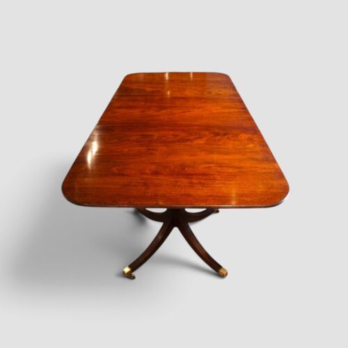 Antique extending mahogany dining table shown with its twin pillar base.