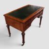 Elegant antique Holland & Sons library writing table with figured mahogany, carved details and brass castors.