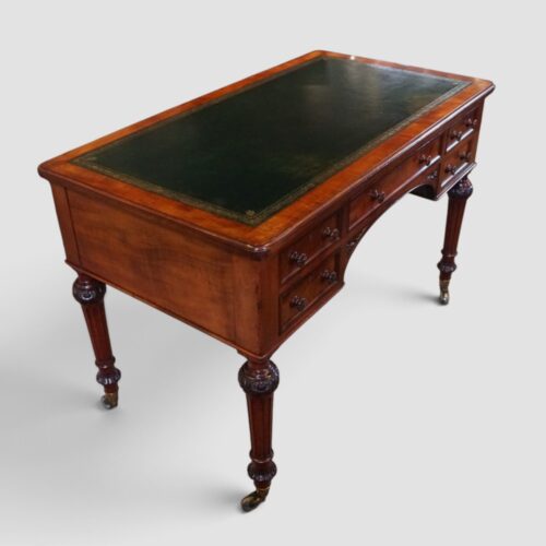 Elegant antique Holland & Sons library writing table with figured mahogany, carved details and brass castors.