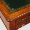 Antique Victorian pedestal writing table in richly figured mahogany with nine drawers and leather writing surface.