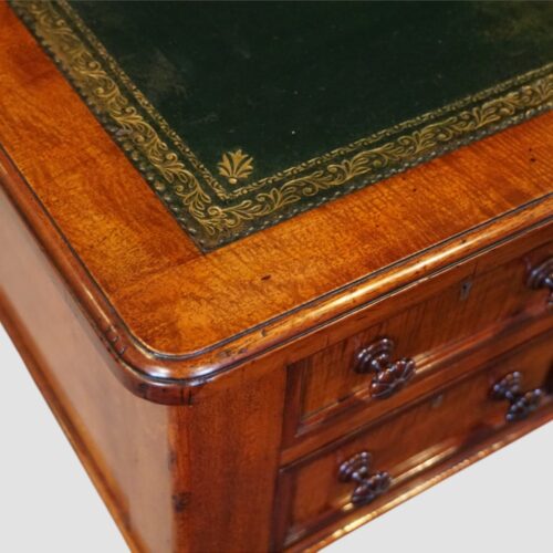 Antique Victorian pedestal writing table in richly figured mahogany with nine drawers and leather writing surface.